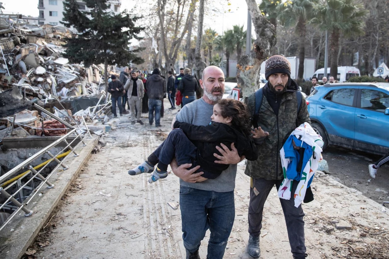 A man carries a child from a collapsed building in Hatay, Turkey. A 7.8-magnitude earthquake hit near Gaziantep, Turkey, in the early hours of Monday, followed by another 7.5-magnitude tremor just after midday.